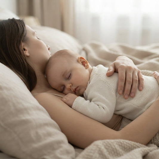 Cododo sécurisé : maman aux cheveux bouclés endormie près de son nouveau-né sur une literie blanche douce