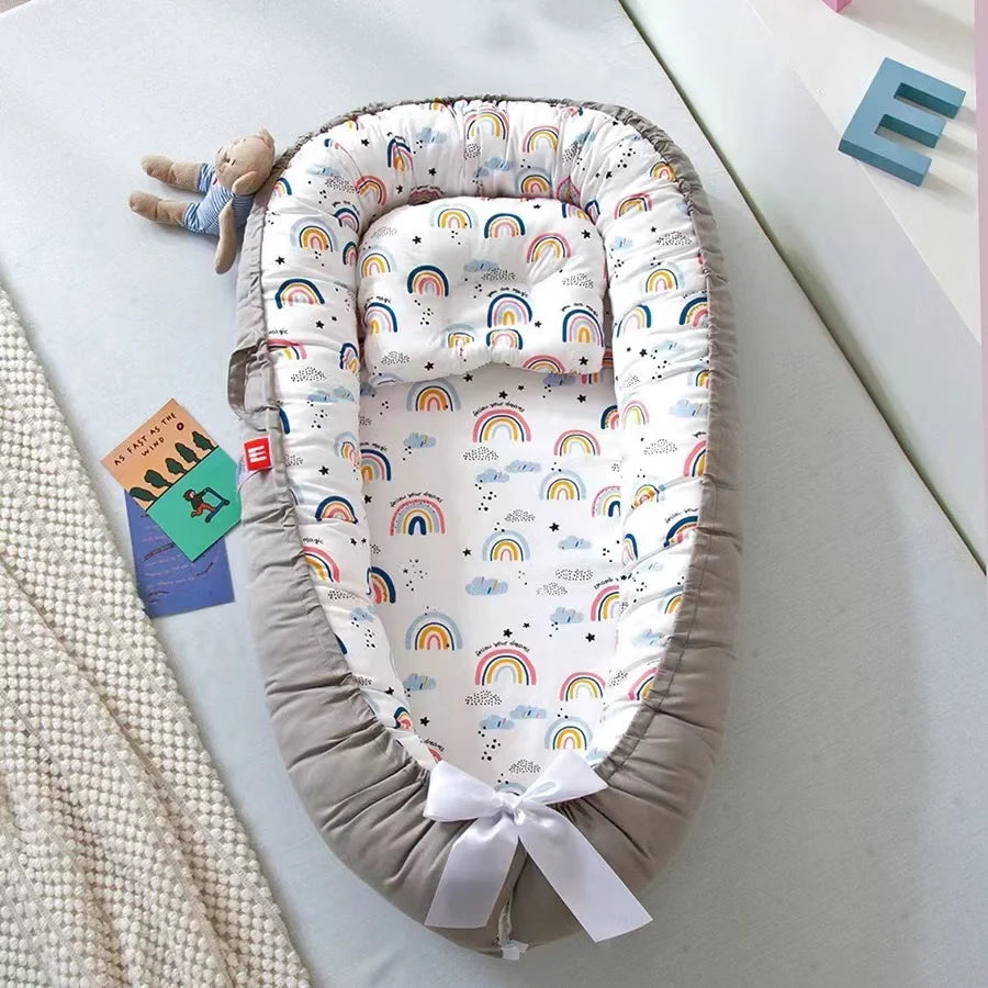 Cocon bebe gris avec motifs arc-en-ciel et oreiller assorti.