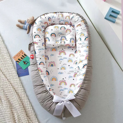 Cocon bebe gris avec motifs arc-en-ciel et oreiller assorti.