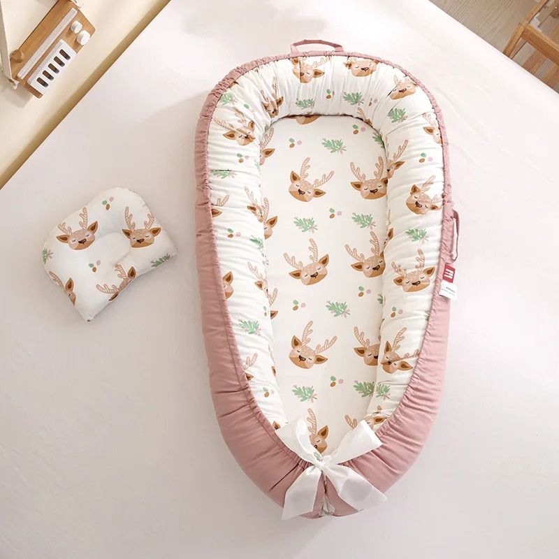 Cocon bebe rose avec motifs cerfs et oreiller assorti.