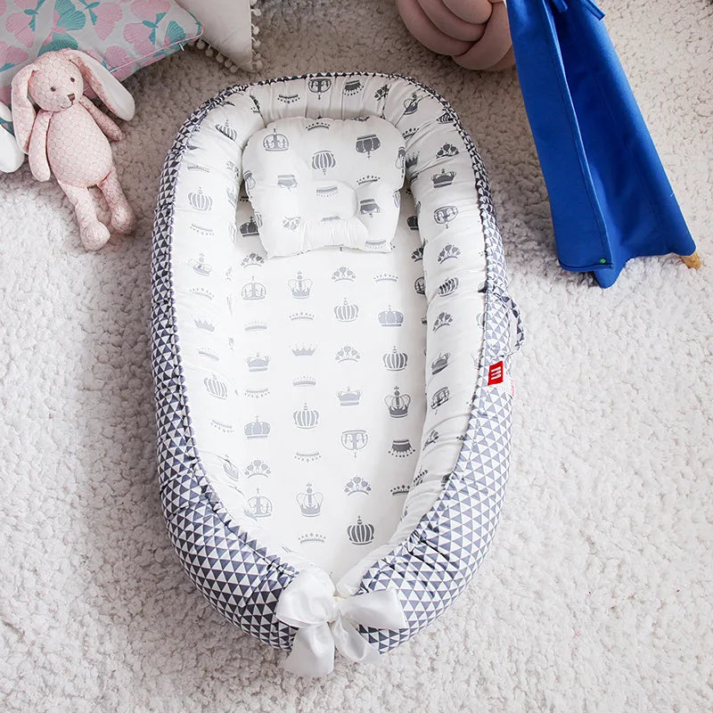 Cocon bebe gris avec motifs couronnes et oreiller assorti.