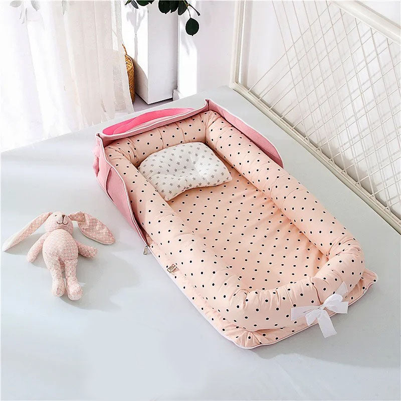 Cocon bebe rose avec motifs de petits pois noirs.