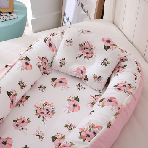 Couffin bébé avec motifs floraux roses, coussin assorti inclus.