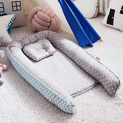 Couffin bébé confortable et design en tissu gris à étoiles blanches avec des rebords rembourrés et un coussin assorti, doté d'un motif chevron bleu sur les côtés, idéal pour offrir un espace douillet et sécurisé aux nouveau-nés, détaché et installé dans une chambre décorée avec des coussins et un tipi bleu en arrière-plan.