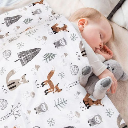 Couverture bébé douce et respirante avec des motifs d’animaux de la forêt, enveloppant un bébé endormi tenant une peluche, pour un sommeil paisible et réconfortant.