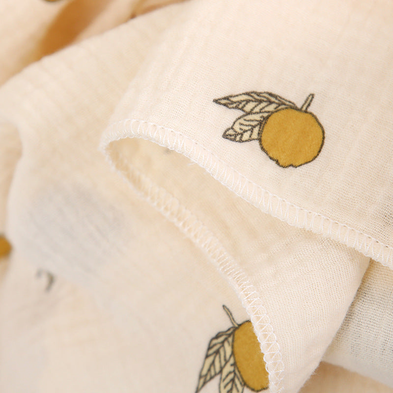 Couverture emmaillotage bébé en coton doux avec un motif délicat de petits citrons jaunes accompagnés de feuilles vertes, apportant une touche naturelle et élégante pour un look à la fois minimaliste et apaisant.