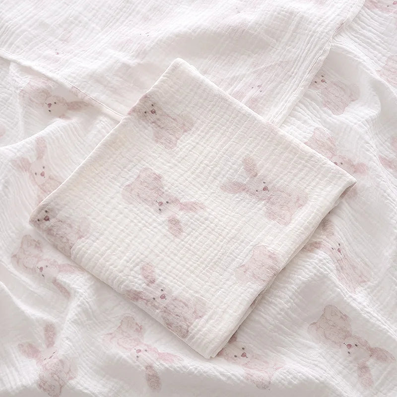 Couverture emmaillotage bébé en mousseline de coton blanc ultra douce, décorée de jolis motifs de lapins de couleur pastel, idéale pour envelopper délicatement votre nouveau-né et apporter chaleur, sécurité et confort au quotidien.