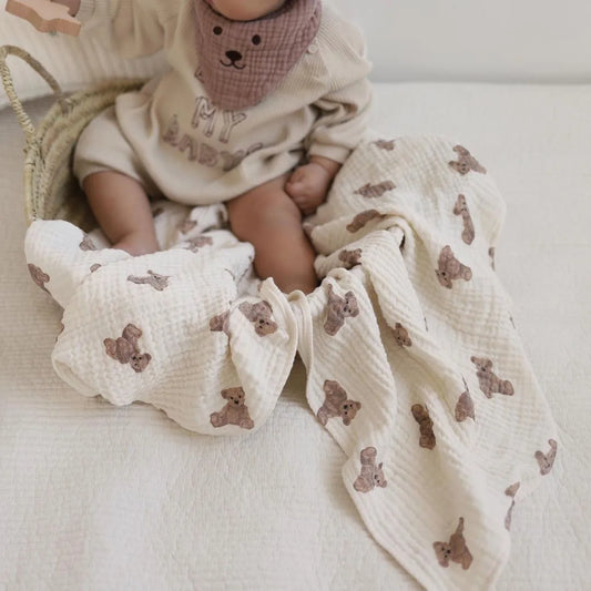 Couverture emmaillotage bébé en mousseline de coton bio ultra douce, ornée de jolis motifs oursons beige, parfaite pour envelopper votre nouveau-né avec confort et chaleur — idéale comme couverture d’allaitement, de poussette, de jeu ou pour les siestes à la maison, sur un lit ou dans un couffin.