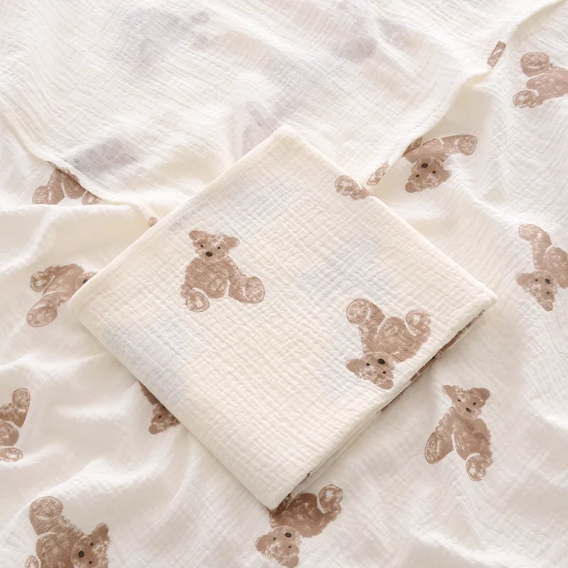 Couverture emmaillotage bébé en mousseline de coton blanc ultra douce, décorée de jolis motifs ourson , idéale pour envelopper délicatement votre nouveau-né et apporter chaleur, sécurité et confort au quotidien.