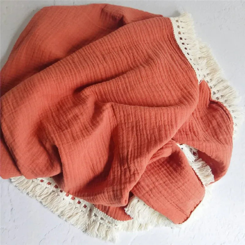 Plaid bébé en mousseline orange avec franges en dentelle bohème, idéal pour envelopper votre enfant de douceur et apporter une touche élégante à sa chambre.