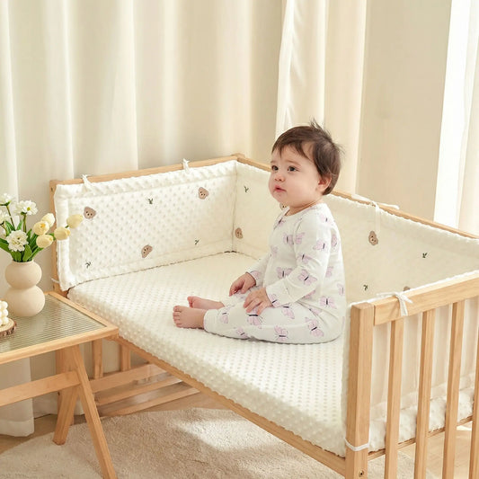 Tour de lit bébé blanc rembourré avec motifs ours installé dans un lit en bois avec bébé assis, protection respirante et sécurisée pour nourrisson