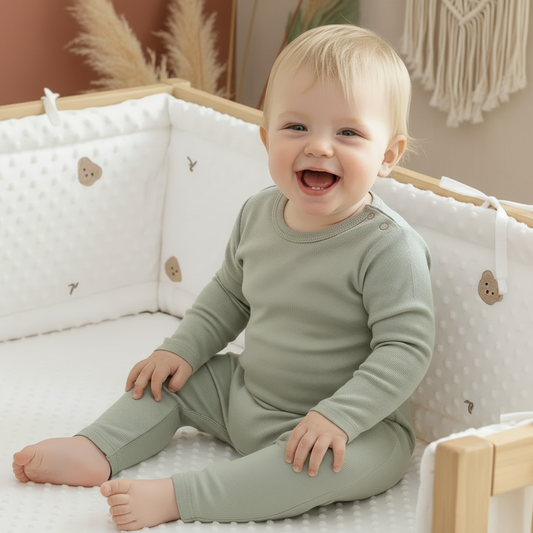 Tour de lit bébé blanc rembourré avec motifs ours installé dans un lit en bois avec bébé assis, protection respirante et sécurisée pour nourrisson