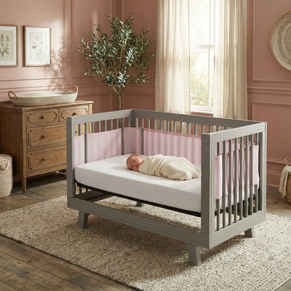 Tour de lit respirant rose installé dans un berceau gris moderne, offrant confort et sécurité pour bébé.