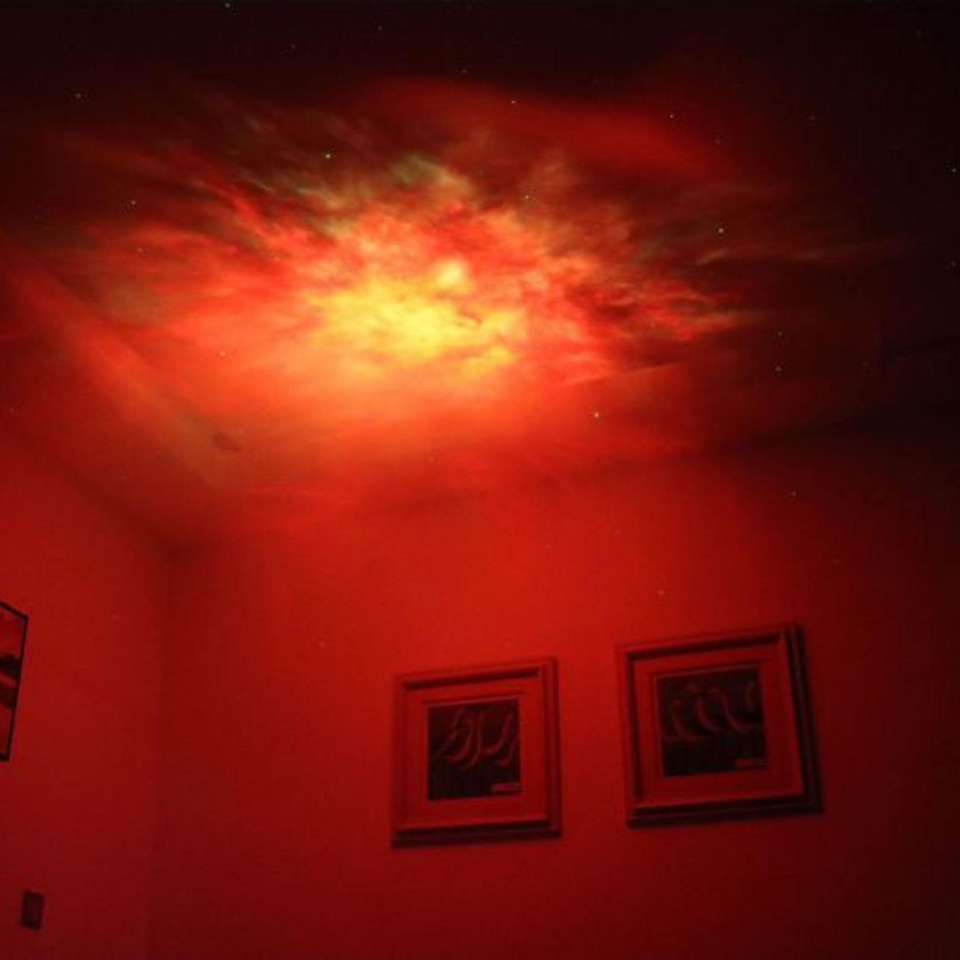 Astronaute projecteur projetant une nébuleuse rouge vibrante au plafond.