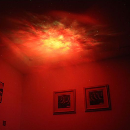 Astronaute projecteur projetant une nébuleuse rouge vibrante au plafond.