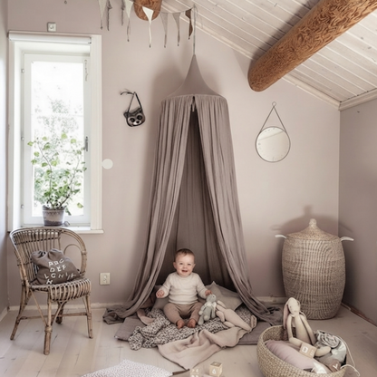 Ciel de lit élégant dans une chambre sous les combles avec poutres apparentes et bébé au sol.