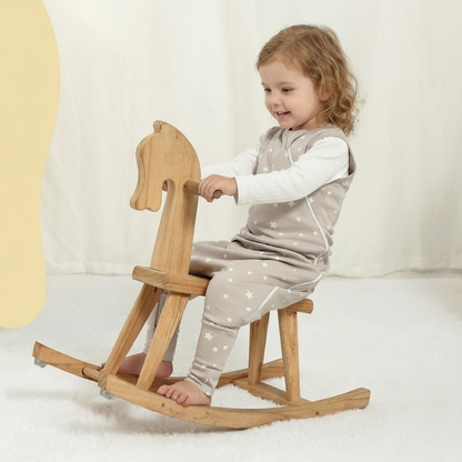 Gigoteuse avec jambes portée par un enfant jouant sur un cheval à bascule en bois.