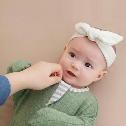 Gigoteuse Bébé vert sauge - Main d'adulte ajustant le col à rayures d'une gigoteuse tricotée portée par un bébé.