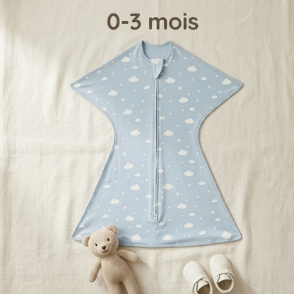 Gigoteuse bébé d'emmaillotage bleue, posée à plat à côté d'un petit doudou, avec l'indication de taille « 0-3 mois ».