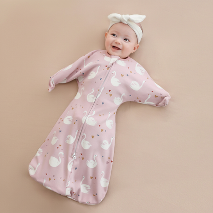 Gigoteuse bébé anti-sursaut rose à motifs cygnes, idéale pour un sommeil apaisé.