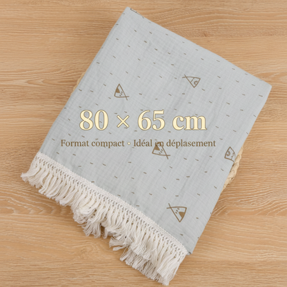 Lange bébé de dimension 80 x 65 cm au format compact idéal pour le déplacement, en mousseline de coton bleu gris avec motifs tipis et franges.