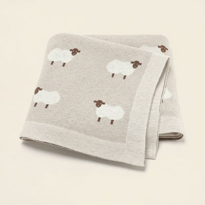 Lange bébé beige sable plié, montrant les détails raffinés et les couleurs naturelles de la collection.