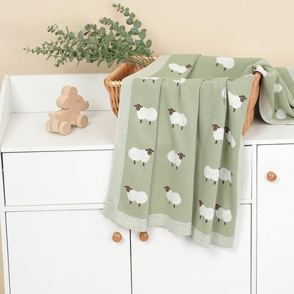 Lange bébé vert disposé sur une commode blanche dans une chambre d'enfant au style boho chic moderne.