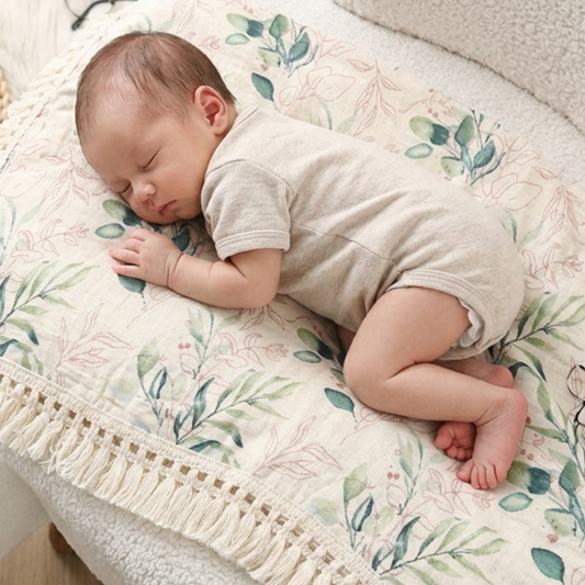 Lange bébé avec motif végétal, un nouveau-né dort paisiblement dessus.