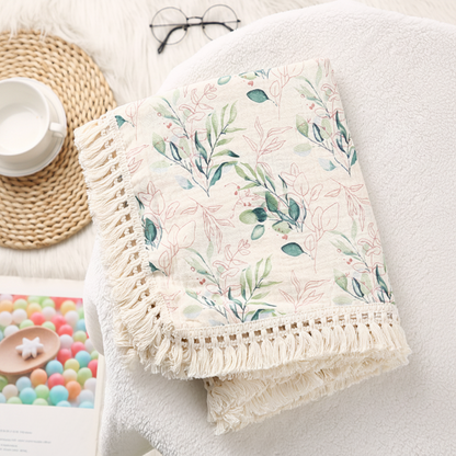 Lange bébé en tissu doux avec détails de franges, plié sur un support.