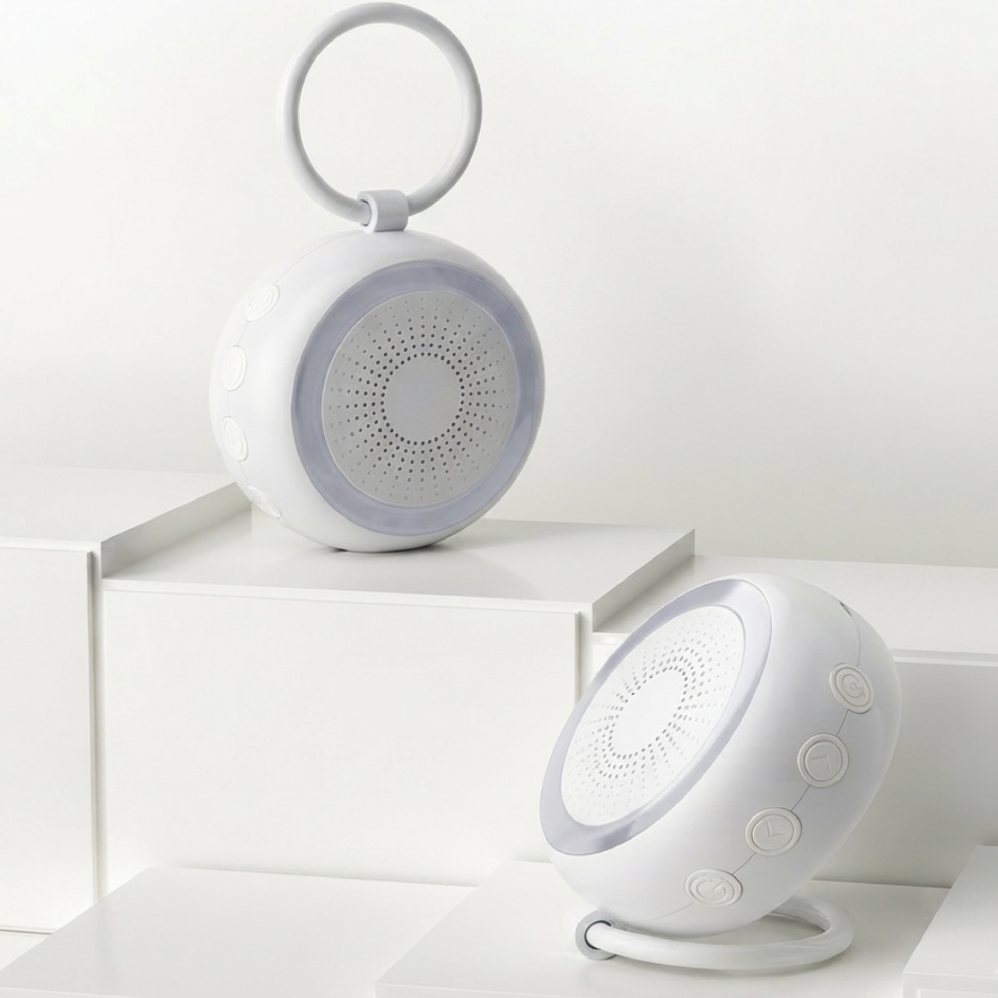 Veilleuse bruit blanc bébé au design rond et blanc, présentée en gros plan sur un présentoir cubique minimaliste.